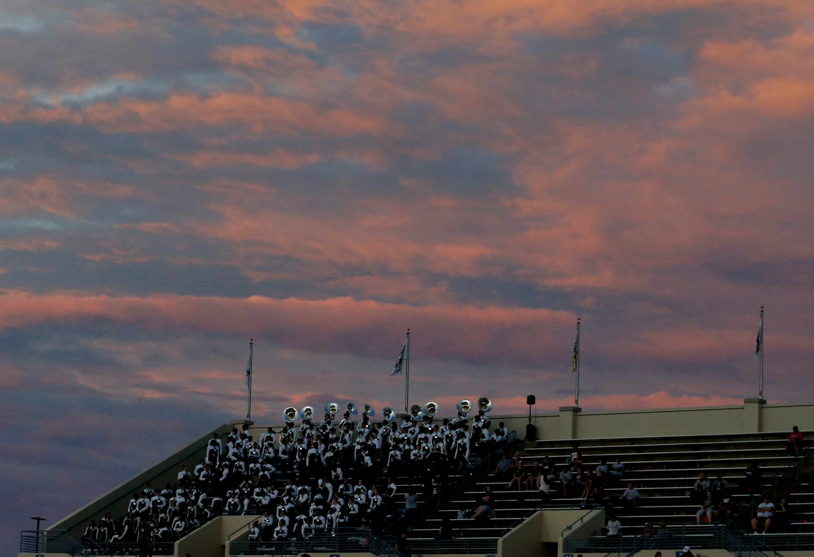 Dissipating post-sunset rain clouds hang over the Lewisville band during the first half of a...