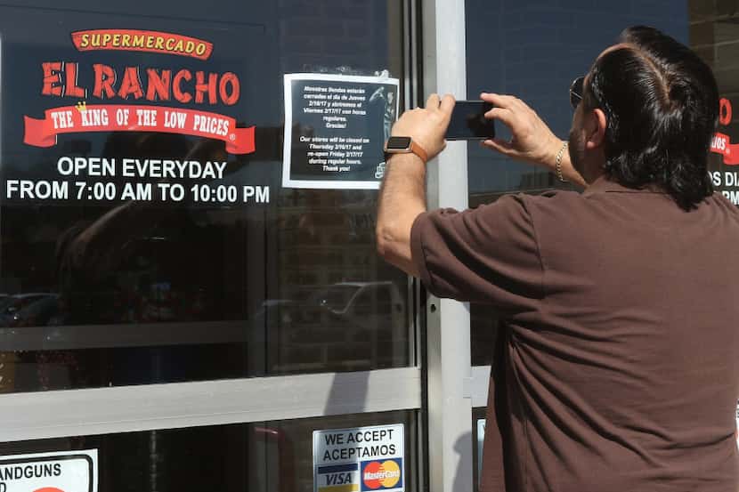 Edgar Maldonado takes a picture of a sign, in English and Spanish, on the door of...
