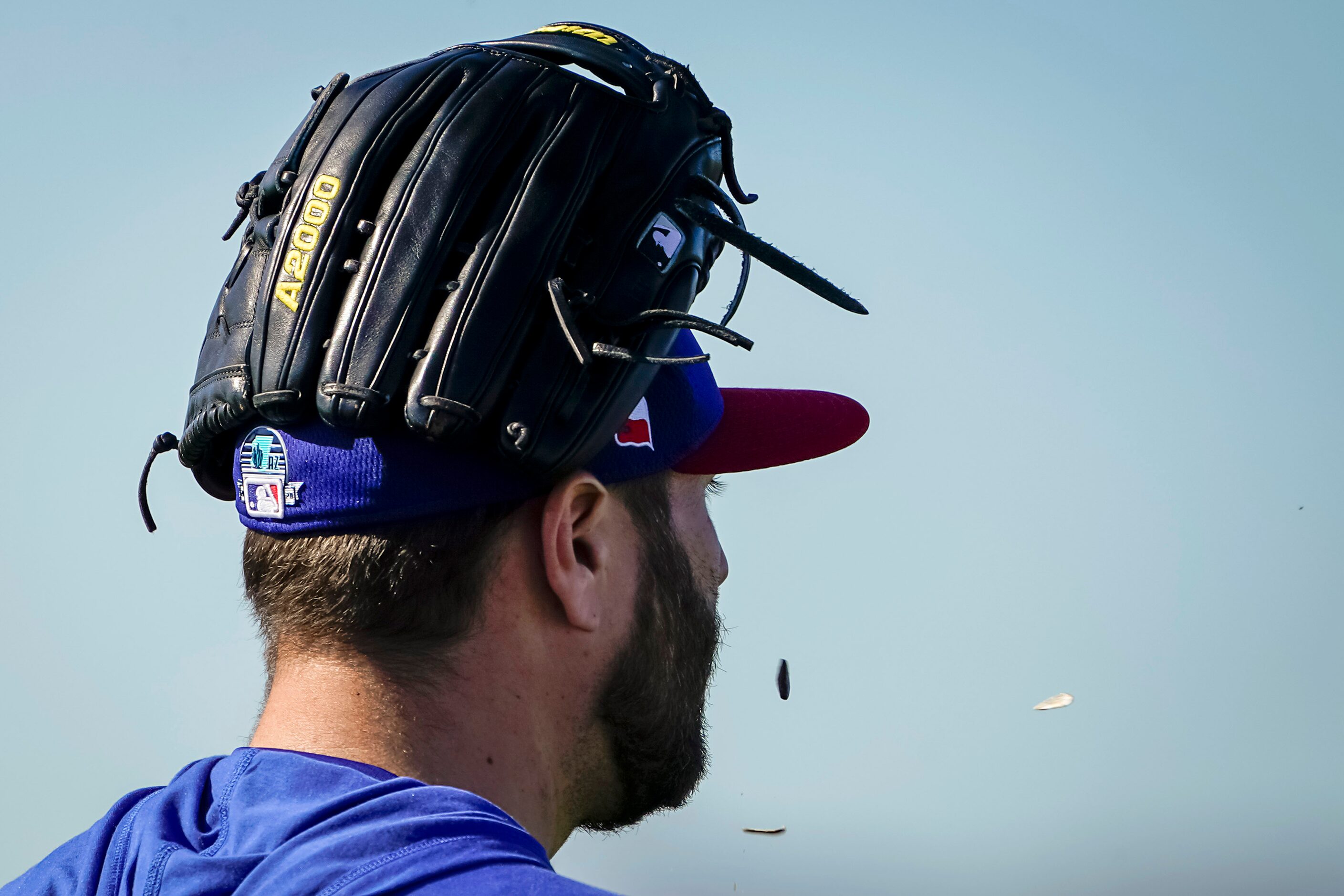 Texas Rangers pitcher Lance Lynn spits sunflower seeds as he walks between fields during a...