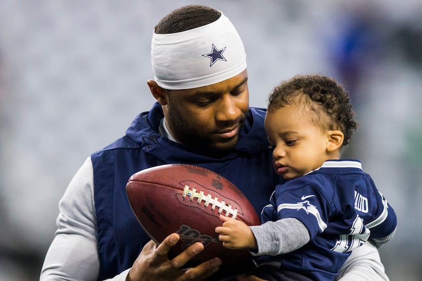 Dallas Cowboys wide receiver Randall Cobb (18) hands a football to his son, Caspian Cyrus...