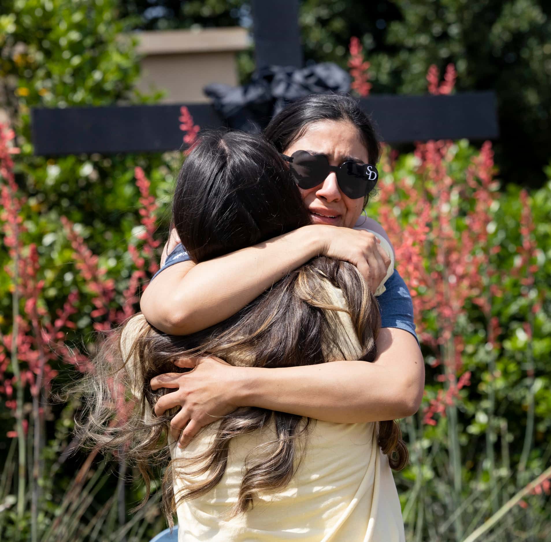 Veronica Rodriguez of Dallas shares an embrace at a memorial outside the mall after a mass...