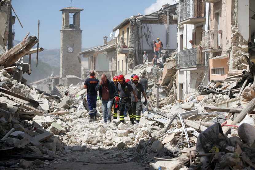 Rescue workers search for survivors in the rubble following an earthquake in Amatrice,...