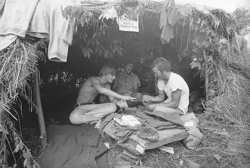 FILE - Music fans seek shelter in a grass hut at the Woodstock Music and Art Festival in...