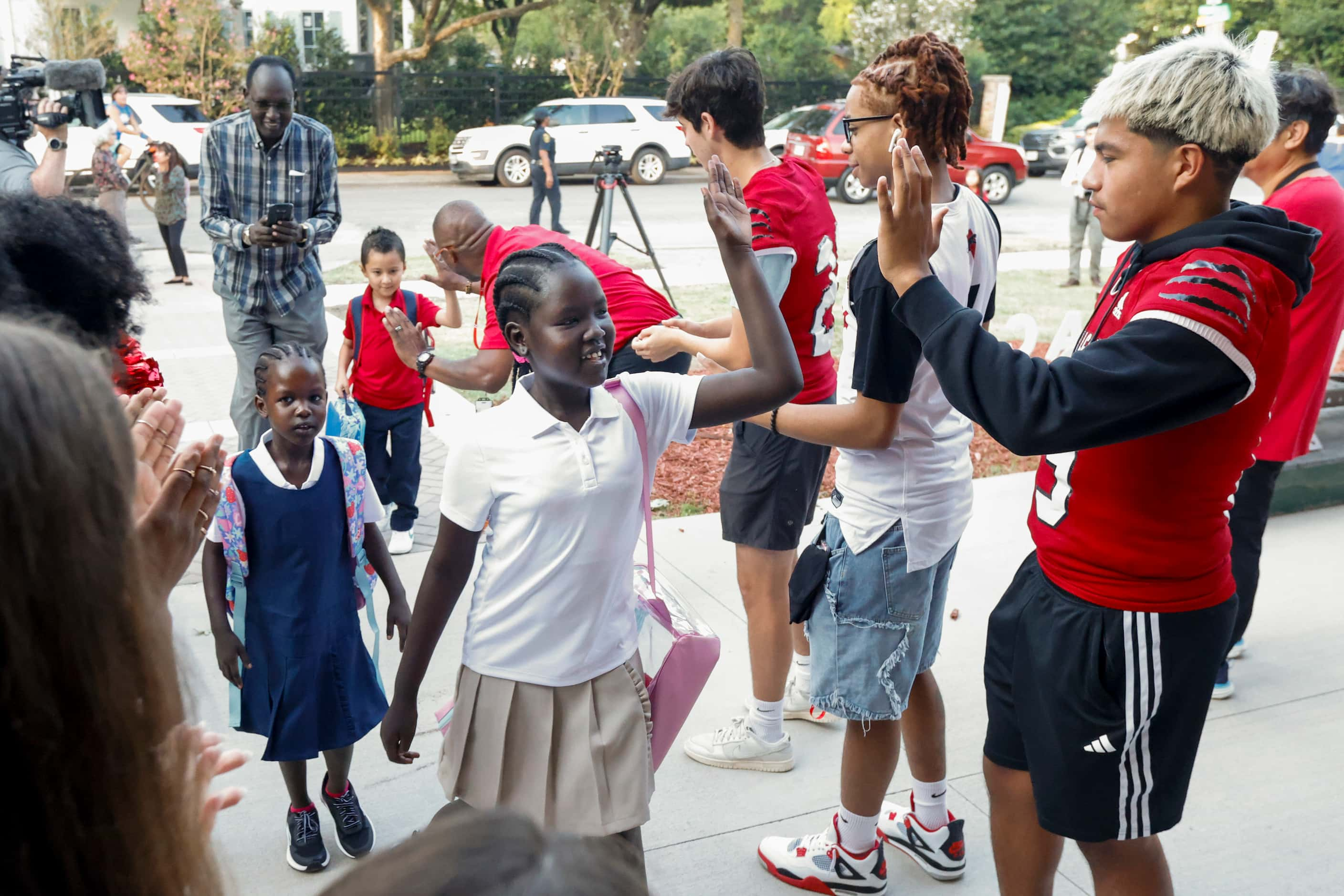 Amuor Mamer, 9 (center), high-fives Hillcrest High School student-athletes during the first...