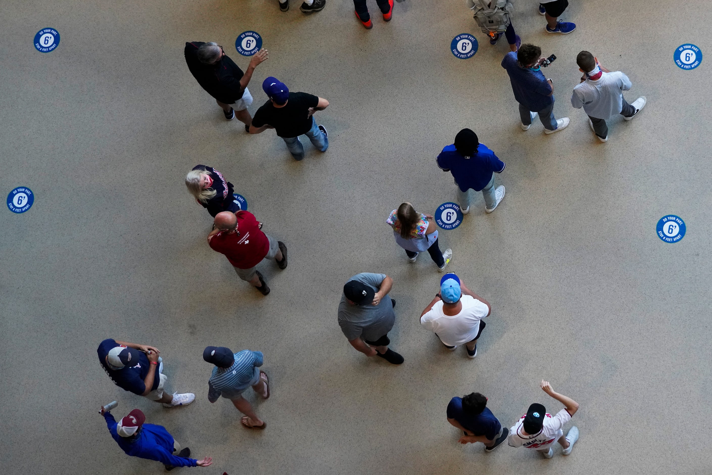 Signs on the floor encourage social distancing as fans line up at a concession stand before...