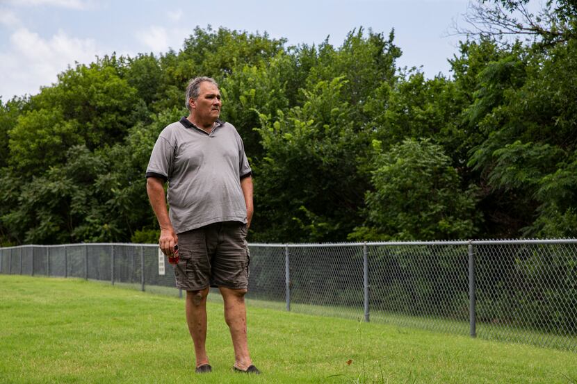 Community activist Don Phillips looks at the fence separating Park Crest Elementary School...