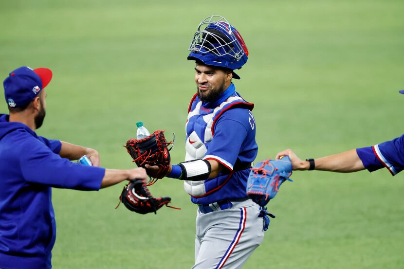 Texas Rangers catcher Robinson Chirinos (center) receives a fist bump from a teammate before...