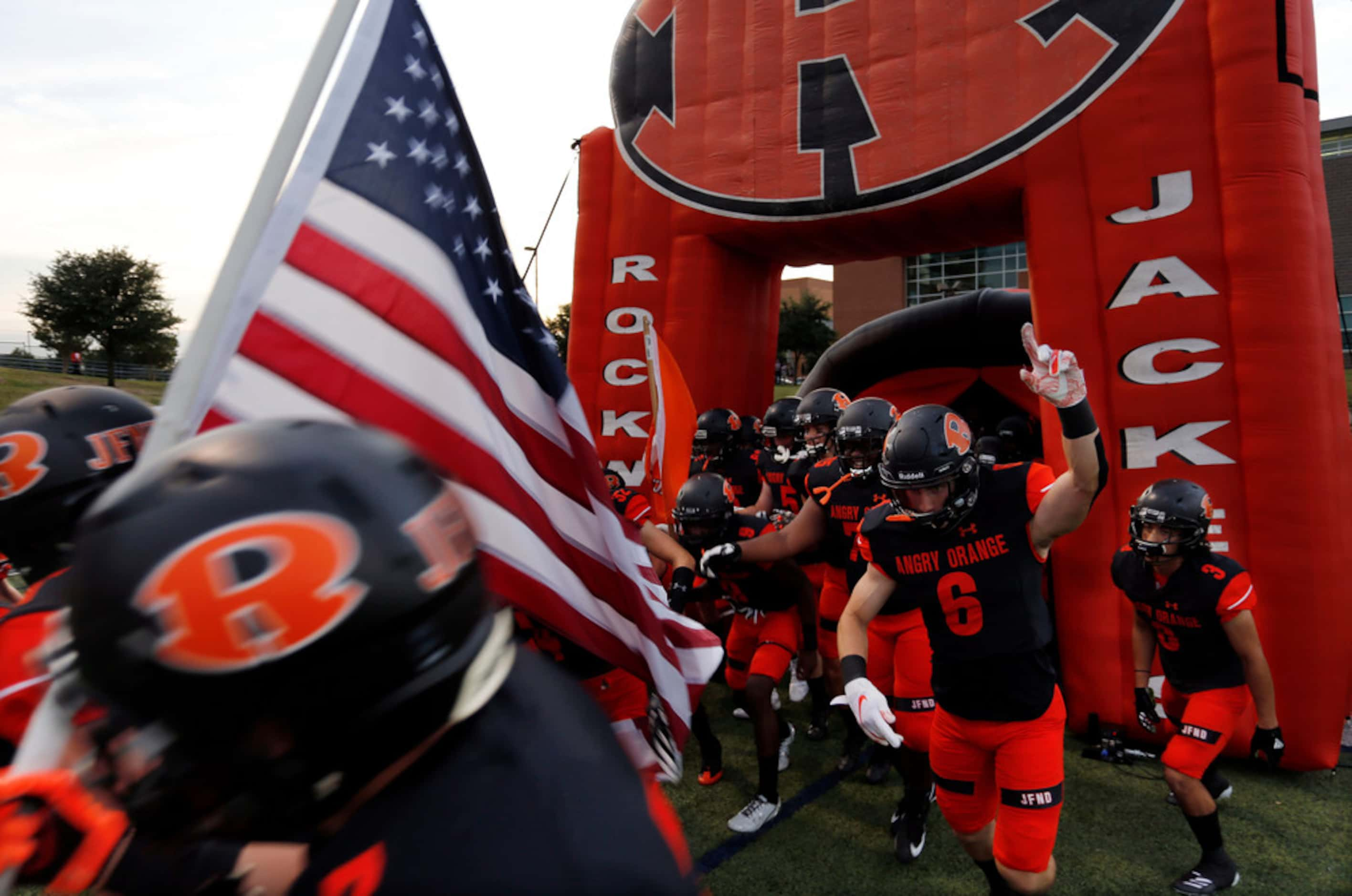 The Rockwall Yellowjackets enter the field before the start of a high school football game...