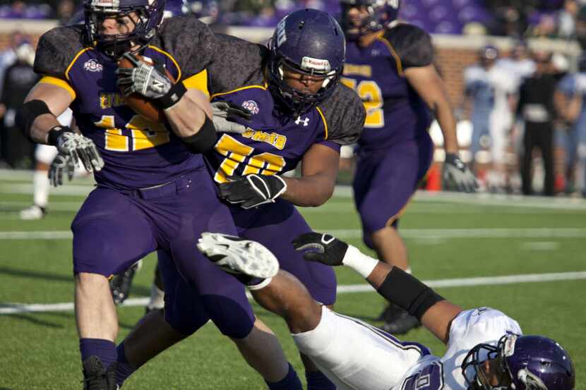 Mary Hardin-Baylor player Elijah Hudson (12) breaks free with the assistance of Kendrick...