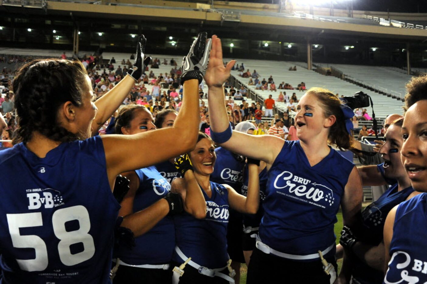 Brunette teammates high-five after winning the 2016 game, 48 to 24, at the Cotton Bowl in...