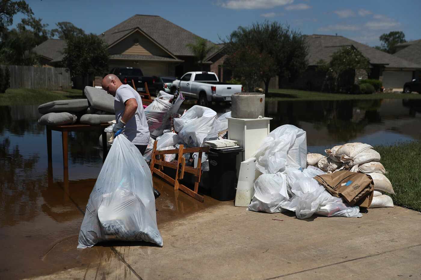 Justin Davison pulls a trash bag full of flood damaged items to a trash pile as he helps a...