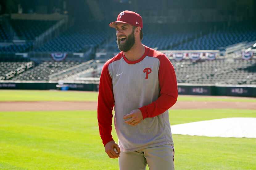 Philadelphia Phillies designated hitter Bryce Harper laughs with teammates during a workout...