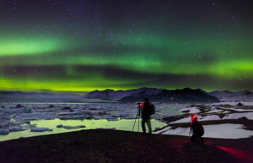 Photographers try to capture the brilliant color of the northern lights at the Jökulsárlón...
