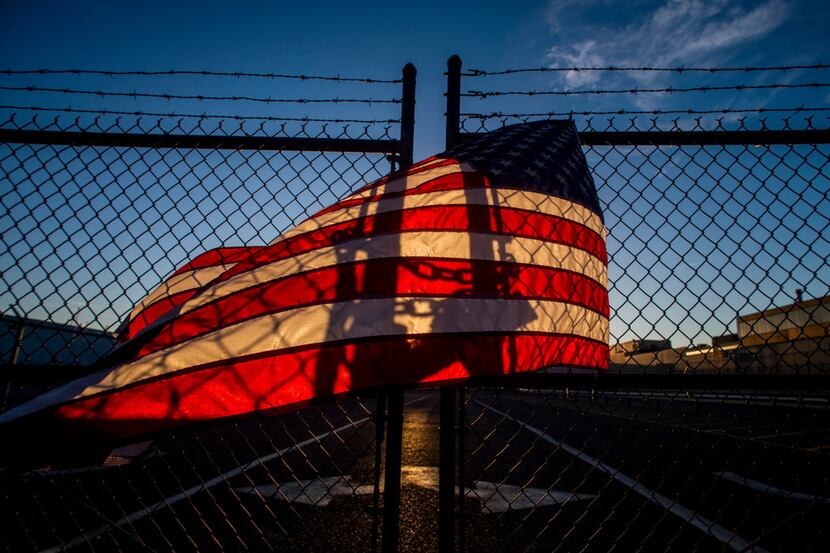 The shadow of a lock glows through an American flag on a locked gate at General Motors'...