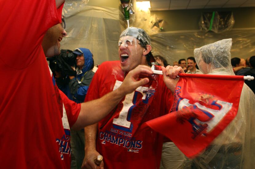 Rangers second baseman Ian Kinsler gets soaked with champaign in the team locker room after...