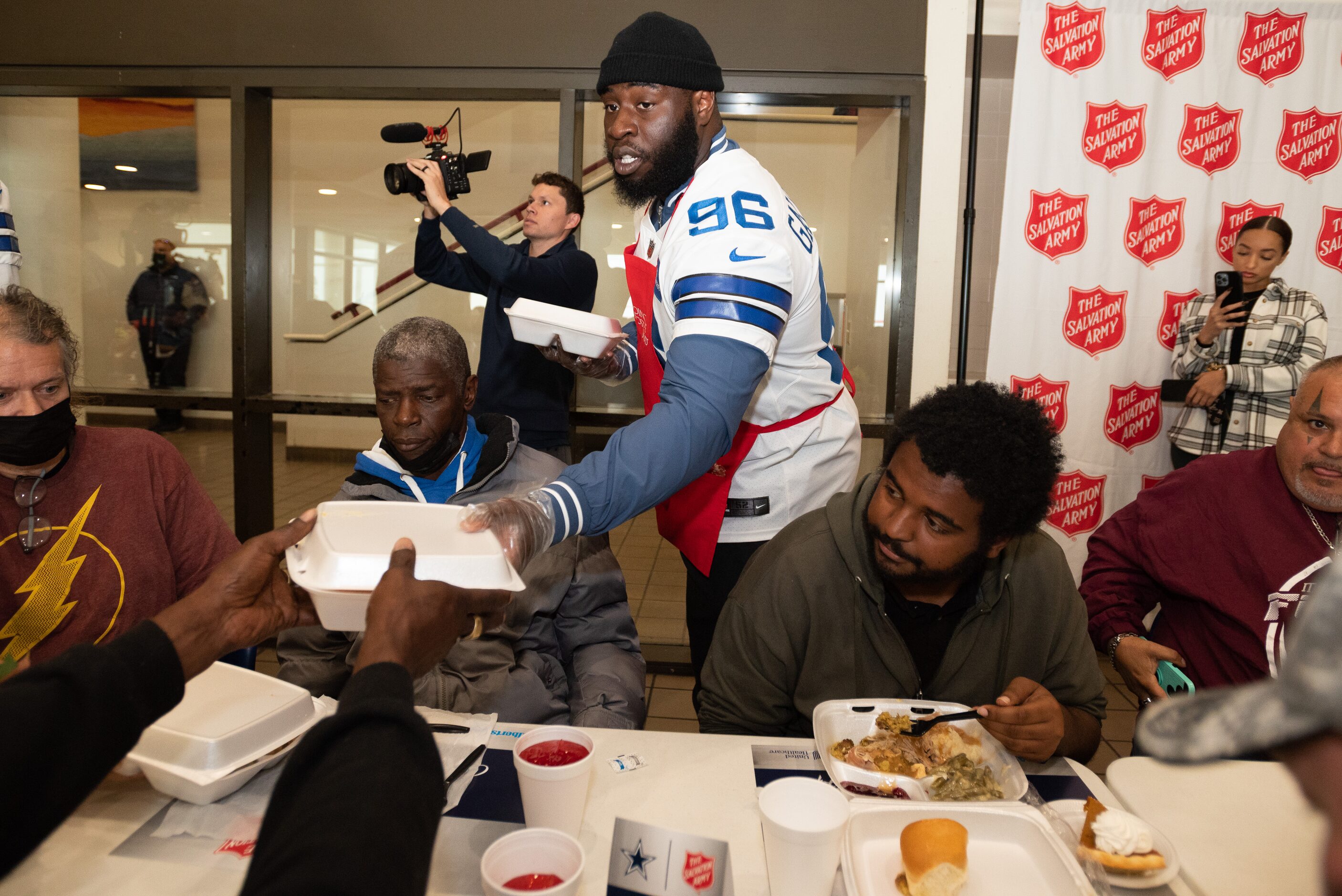 Dallas Cowboys defensive tackle Neville Gallimore hands containers of Thanksgiving meals as...