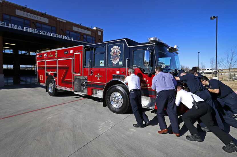 Firefighters push a new fire truck into the fire house of Fire Station No. 1 in Celina,...
