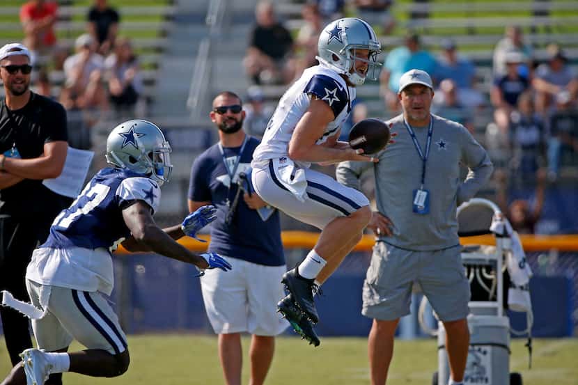 Dallas Cowboys wide receiver Cole Beasley, right, pulls in a pass as he's defended by...