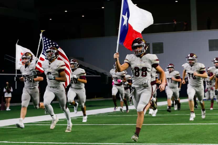 Frisco Heritage football players run out before the start of a game against Frisco...