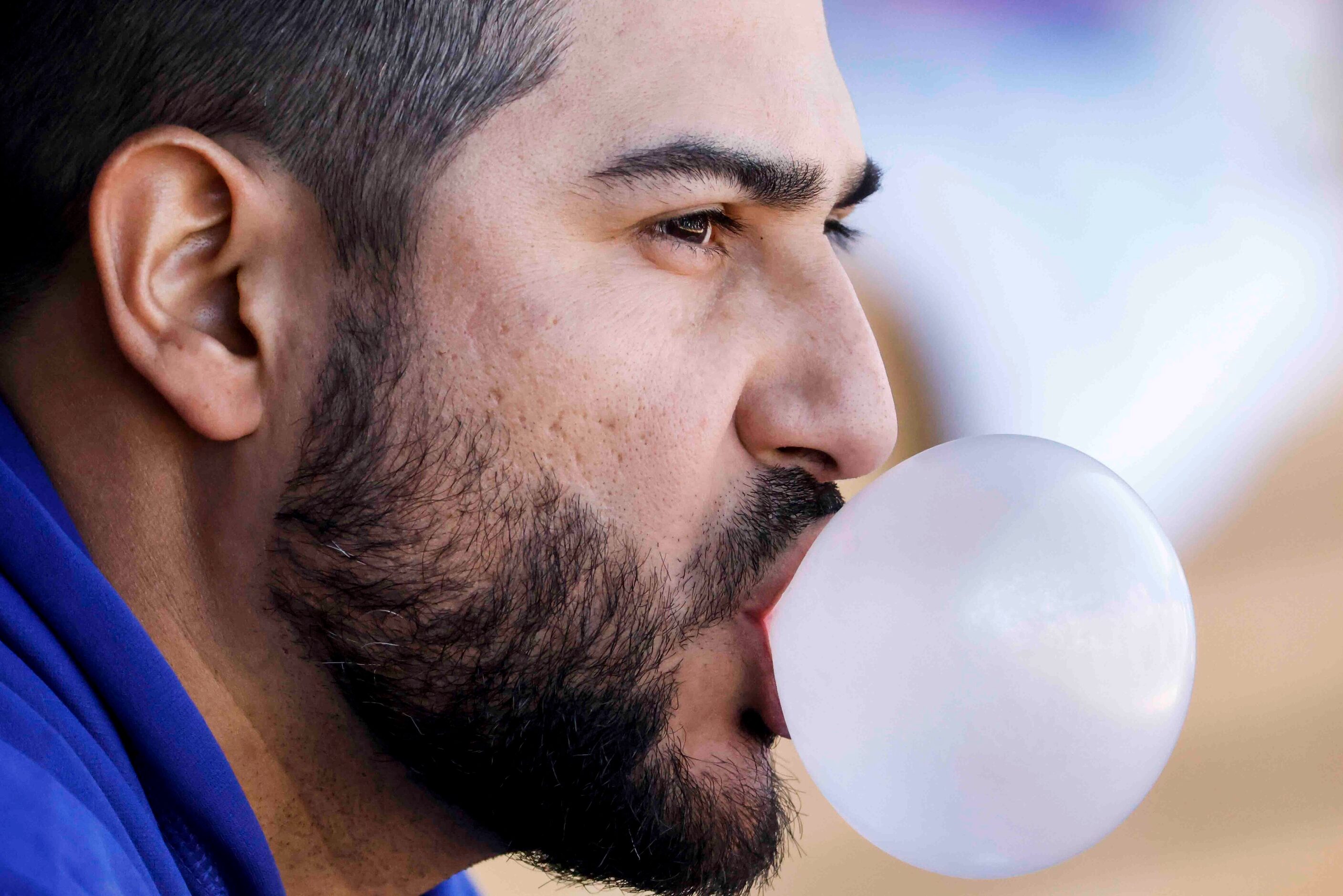 Texas Rangers pitcher Martín Pérez blows a bubble while sitting in the dugout during a...