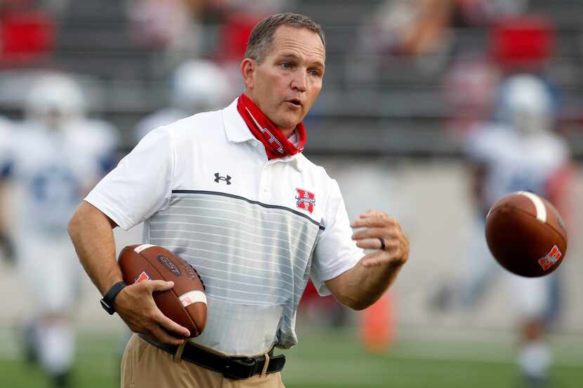 Midlothian Heritage head football coach Lee Wiginton tosses a ball to his players during...