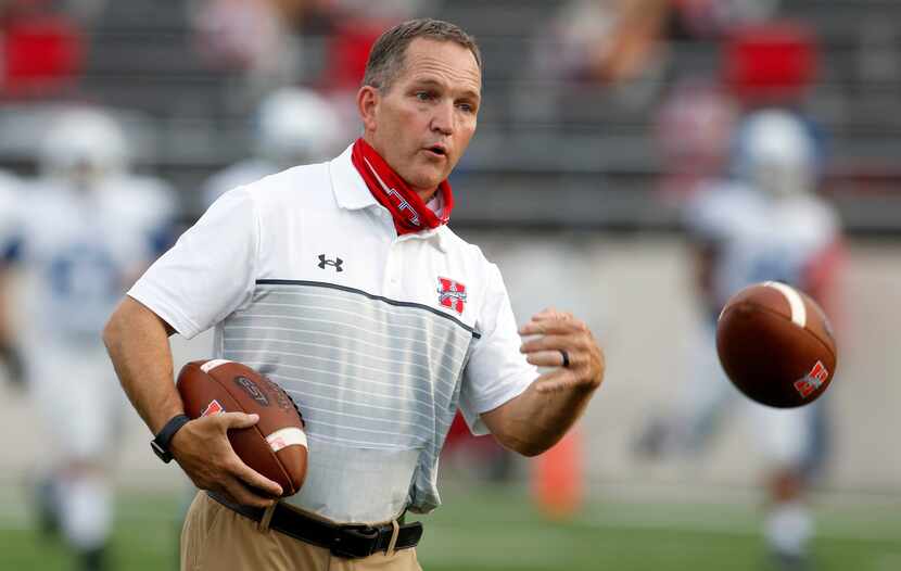 Midlothian Heritage head football coach Lee Wiginton tosses a ball to his players during...