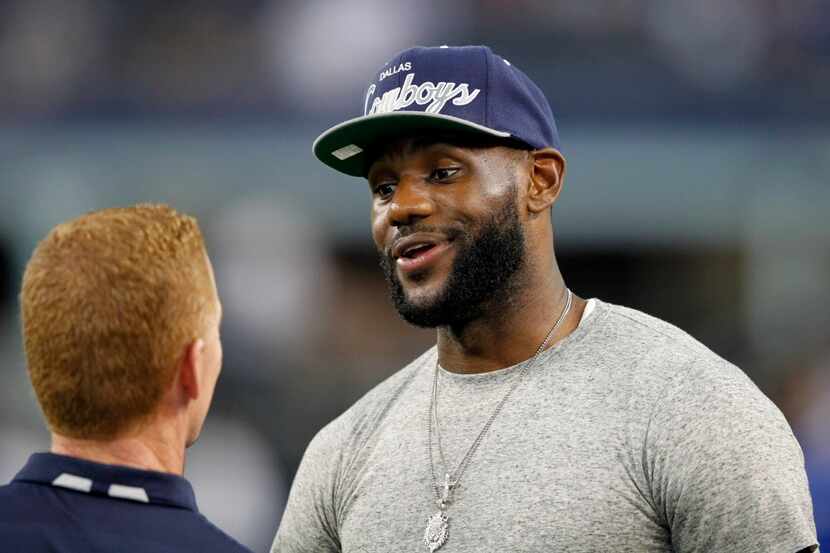 Dallas Cowboys head coach Jason Garrett talks with Miami Heat's Lebron James before a game...