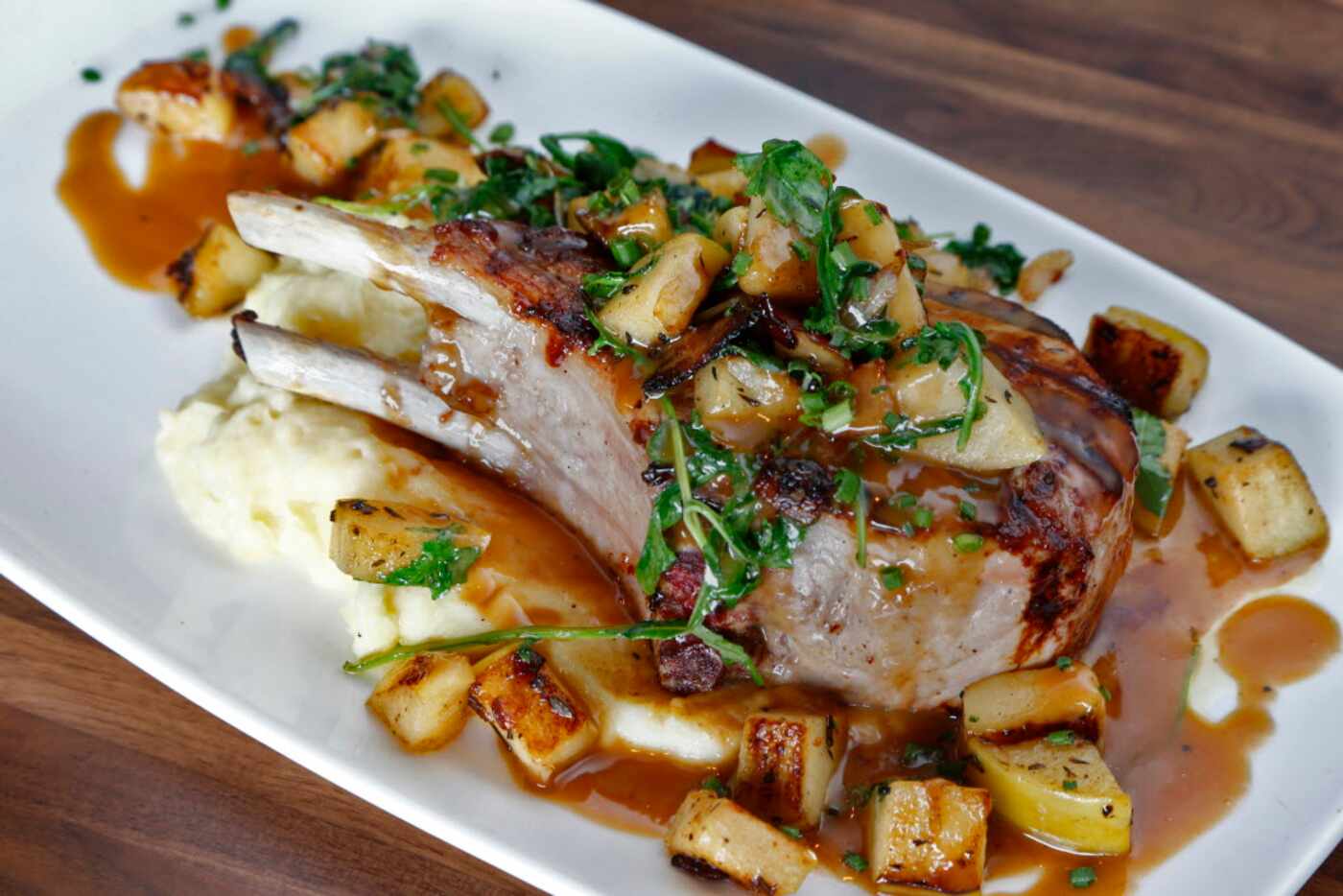 A bourbon-marinated pork chop on mashed potatoes, smothered with arugula-laced ragu of...