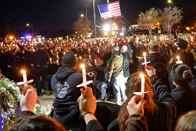 People hold up candles during a candlelight vigil for Terrell police officer Jacob...