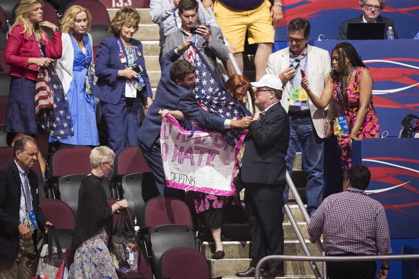 People try to shield a code pink protestor from view after she unfurled a banner reading "No...