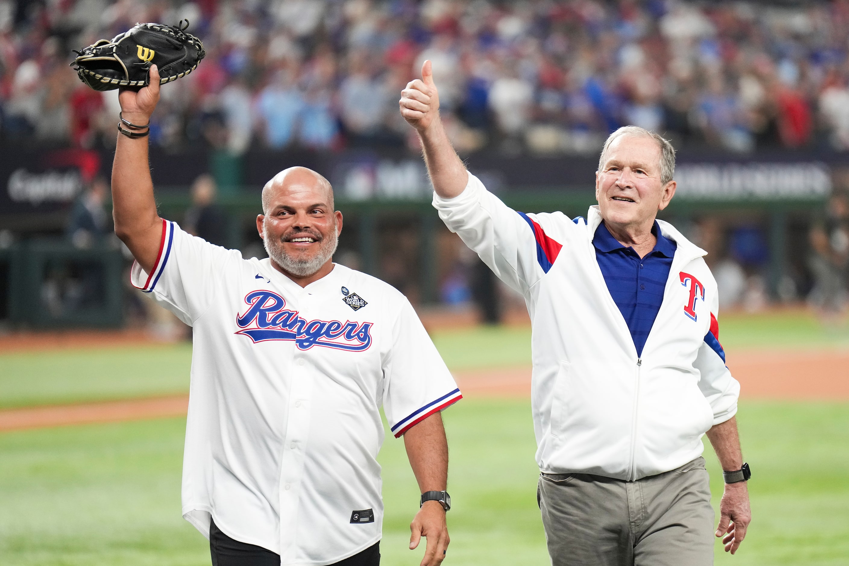 Former Texas Rangers catcher Iván “Pudge” Rodríguez and former President George W. Bush wave...