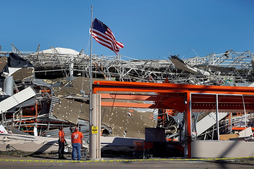 The Home Depot employees A.J. Kobena (center) raised the U.S. flag on the slightly bent...