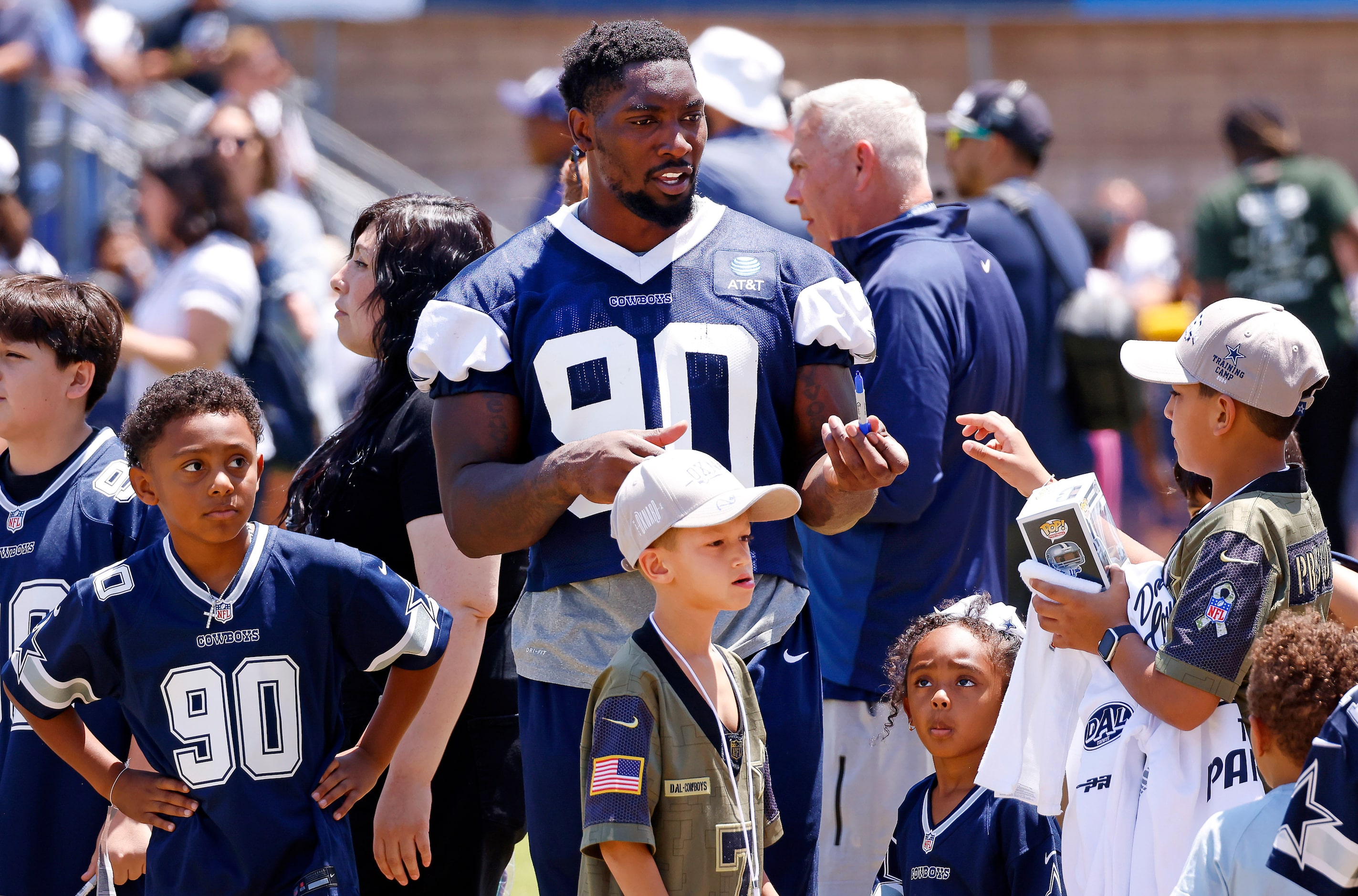 Dallas Cowboys defensive end DeMarcus Lawrence (90) signs autographs for kids following...