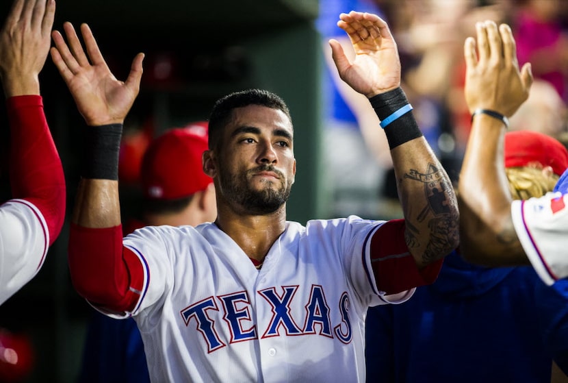 Texas Rangers center fielder Ian Desmond (20) gets high-fives from teammates in the dugout...