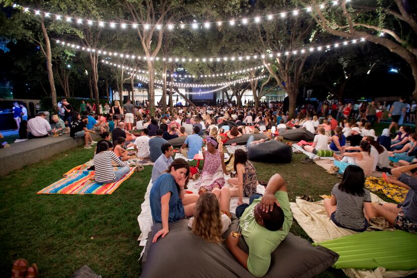 People recline on the lawn at the Nasher Sculpture Center during an outdoor showing of the...