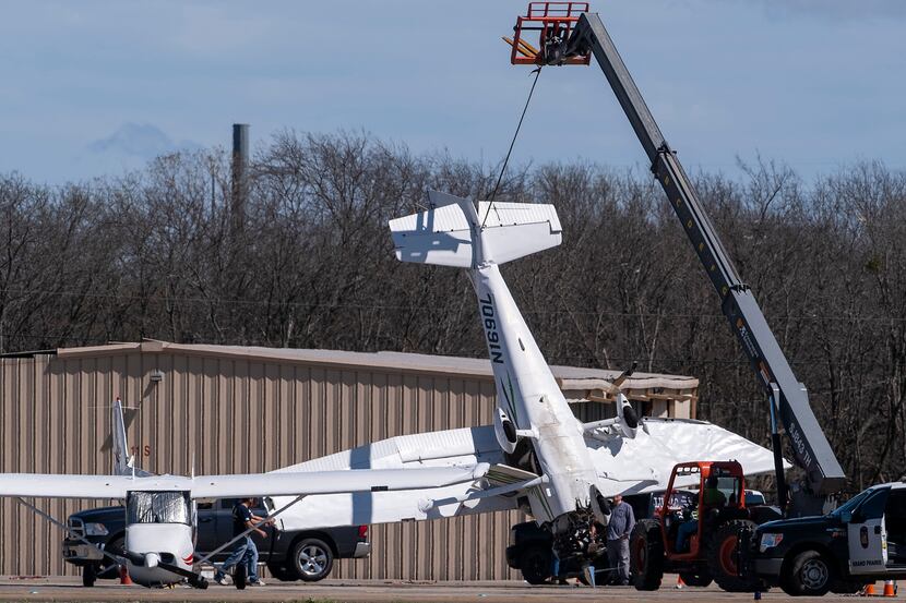 Workers used a crane to clear aircraft that storms early Wednesday damaged at Grand Prairie...