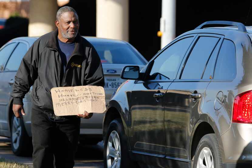 A man panhandles at the intersection I-35E and Market Center in Dallas on Dec. 12, 2016....