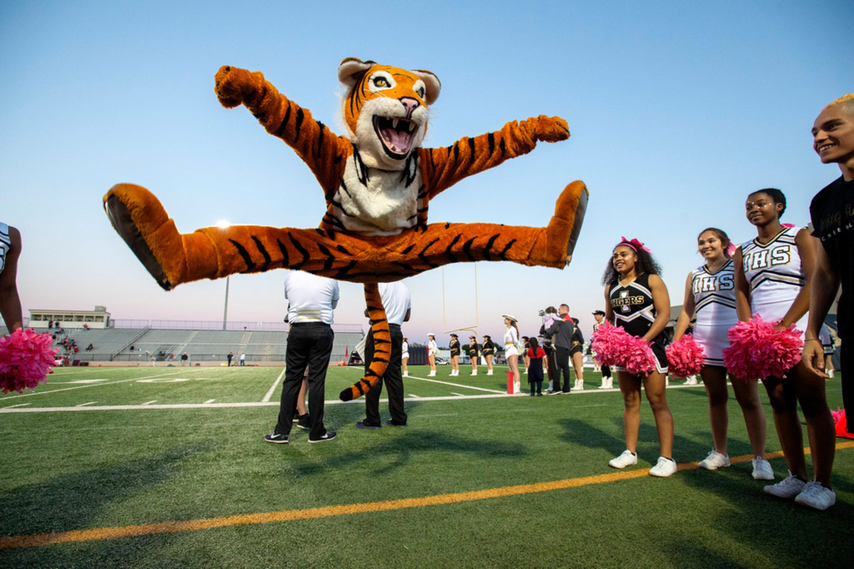 Irving junior Erwin De Leon, dressed as the Tigers' mascot, does a toe-touch before a high...