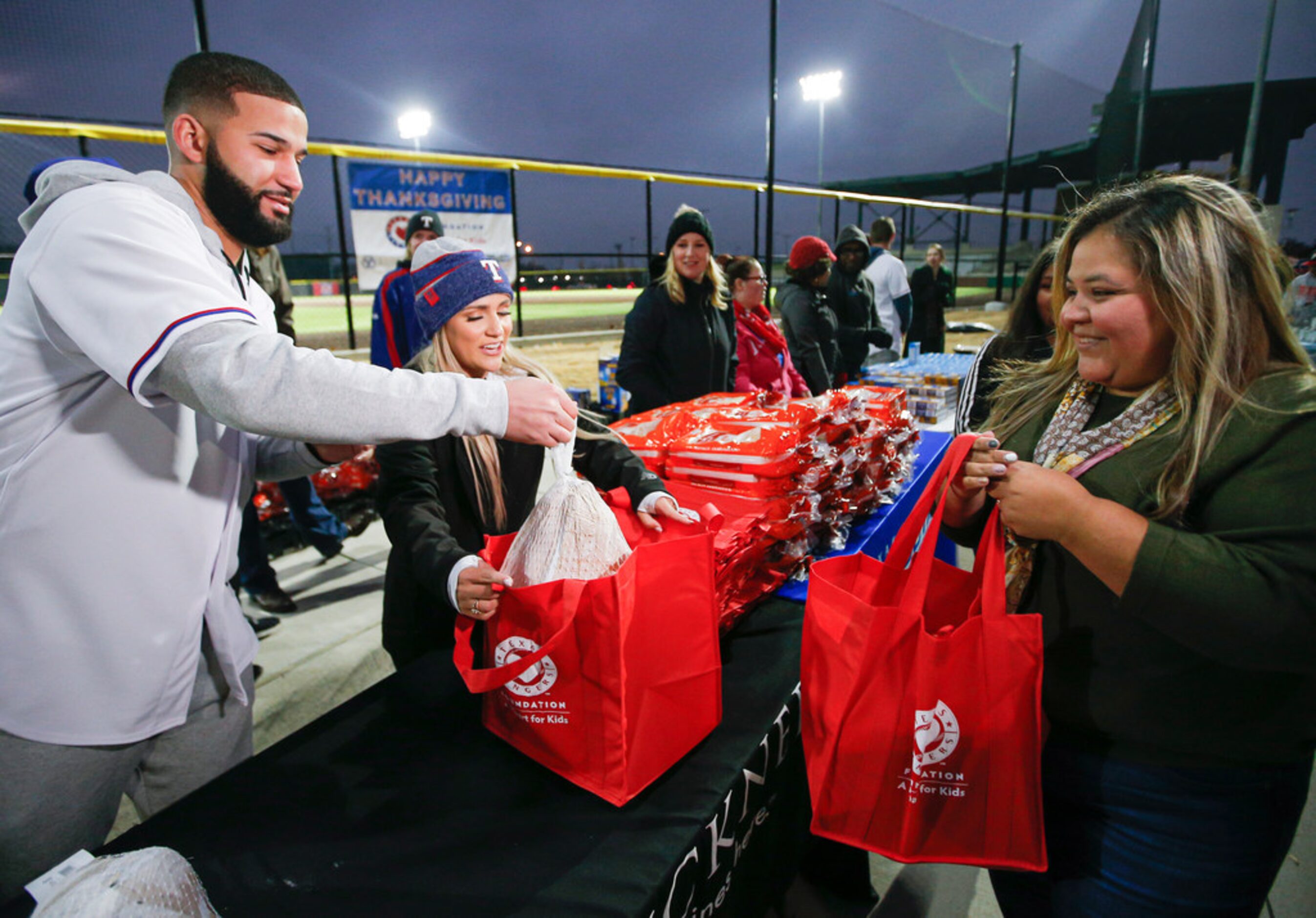 Texas RangersÃ Nomar Mazara bags frozen turkey for Gisela Hernadez, right, at the Texas...