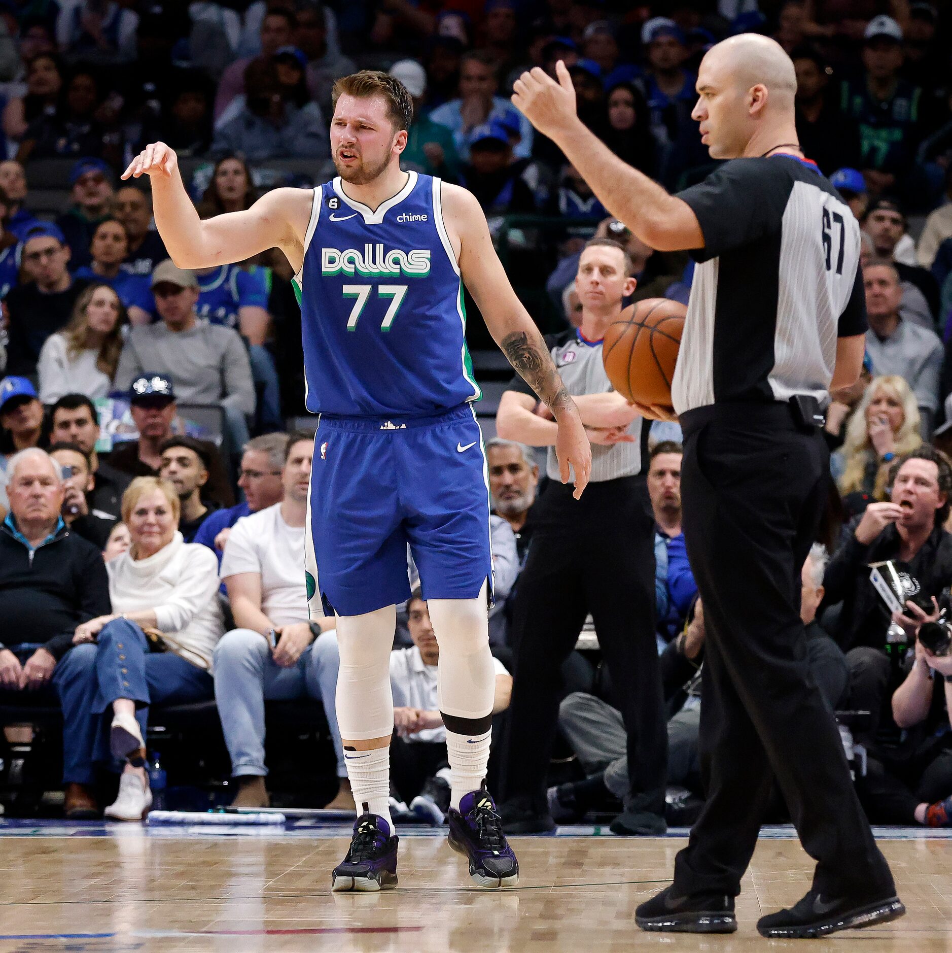 Dallas Mavericks guard Luka Doncic (77) waves off a substitute after he banged his left knee...