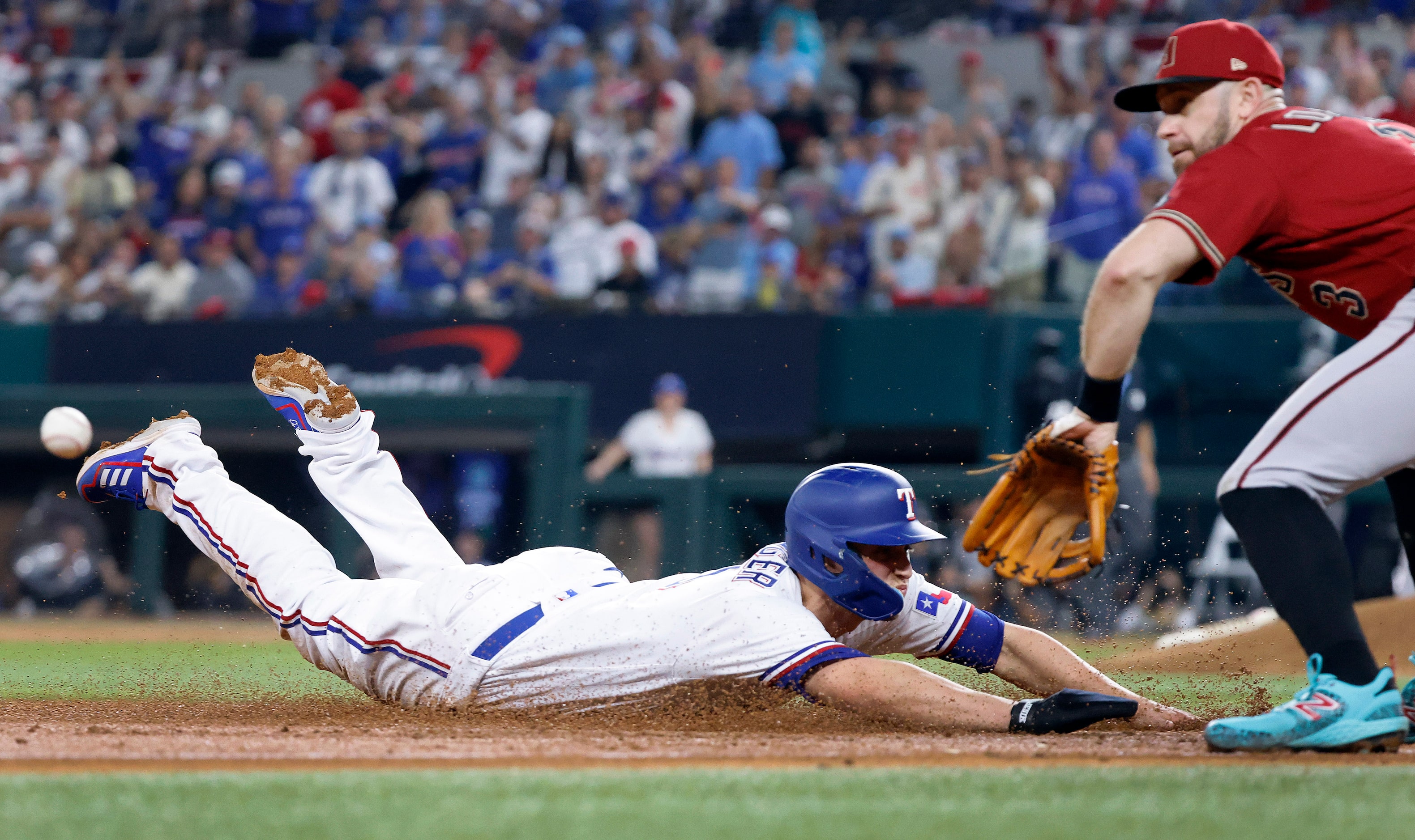 Texas Rangers' Corey Seager slides in safely past Arizona Diamondbacks third baseman Evan...