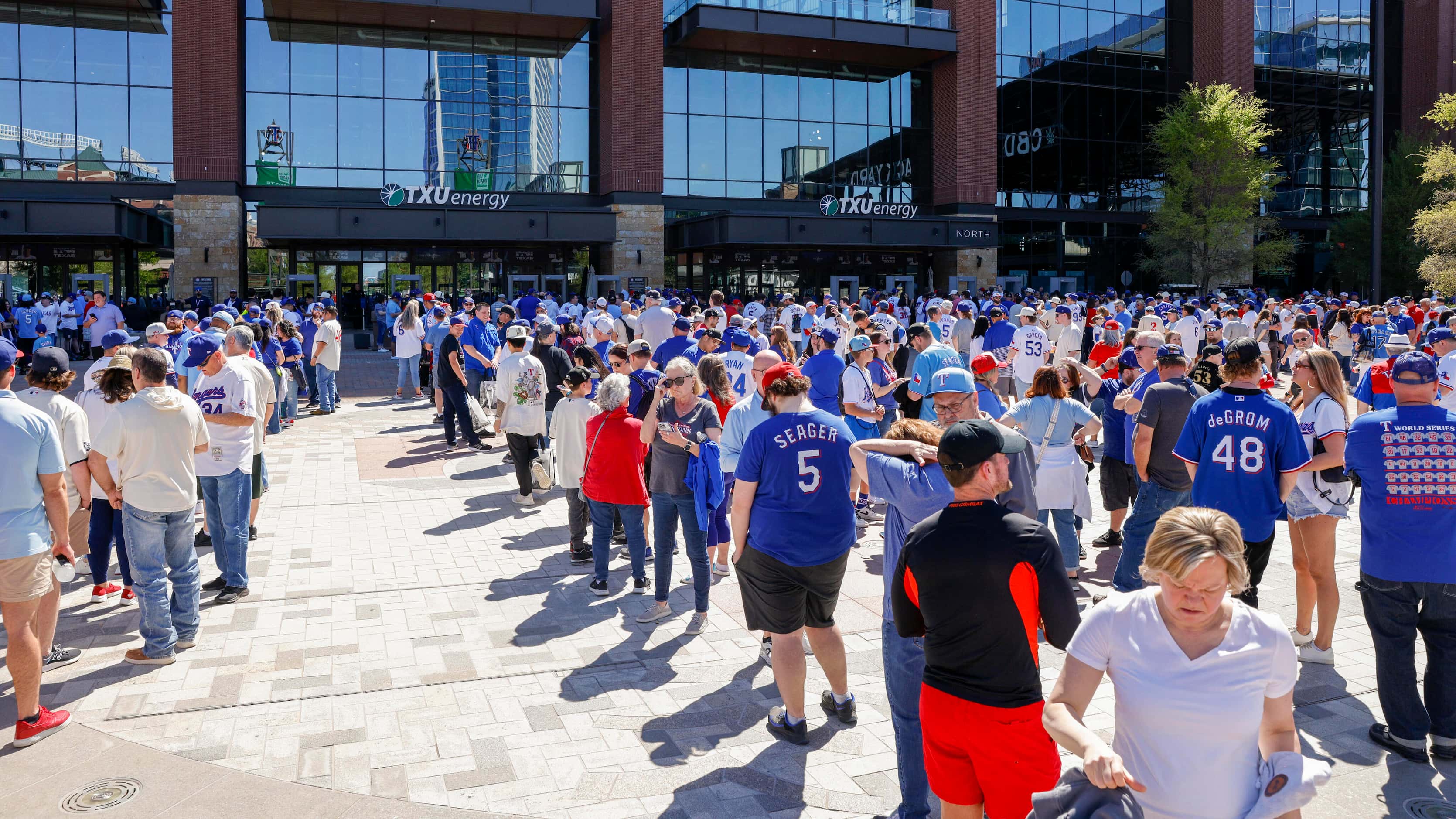 Hundreds of baseball fans wait to enter the ballpark before the season opener between the...