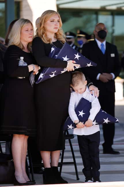 Noel Bergenske Penton (center) and her son Cashton gripped folded U.S. flags following a...