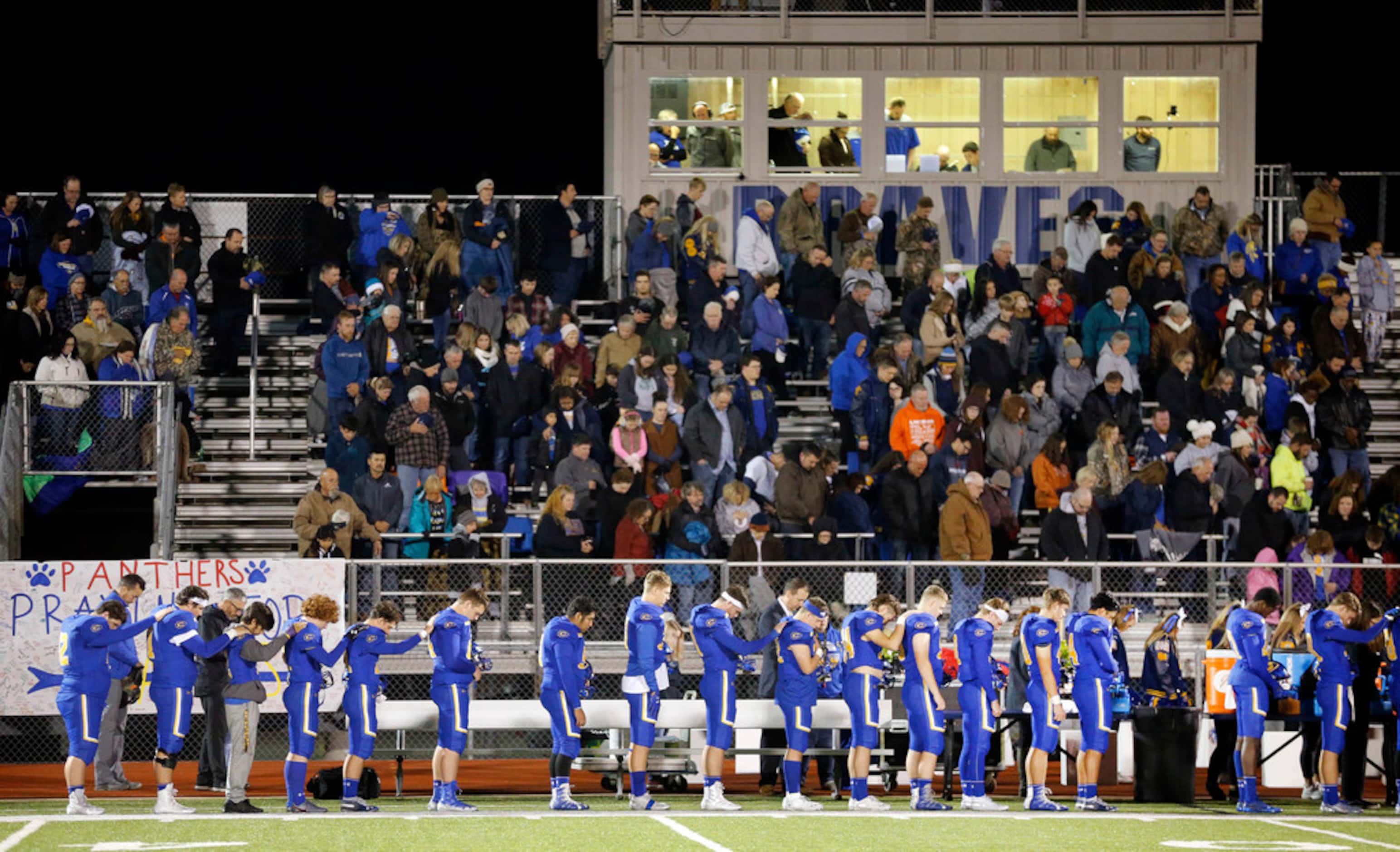 The Community High football team leans on one another during the playing of the national...