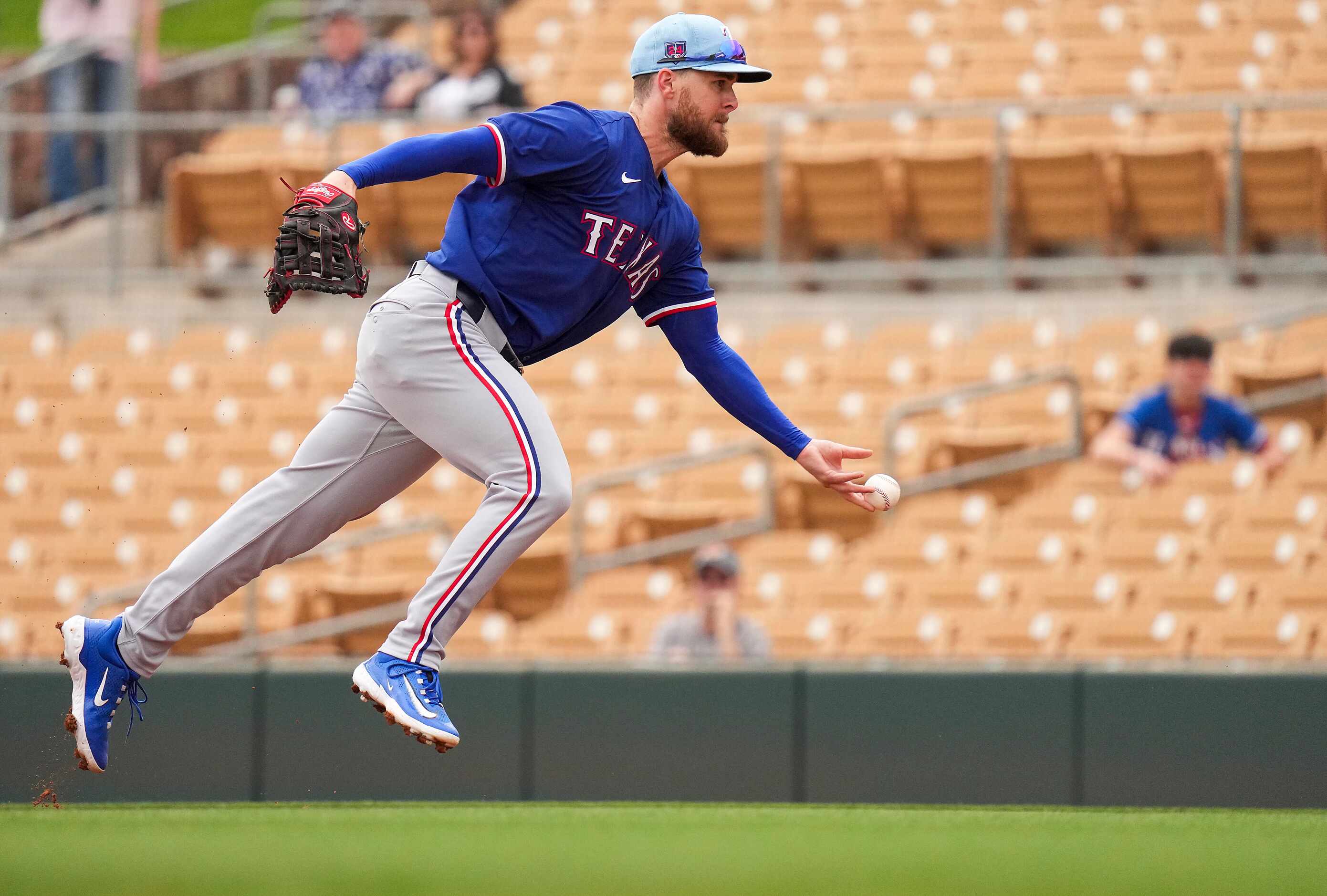 Texas Rangers infielder Jared Walsh flips to the pitcher covering first base to retire...