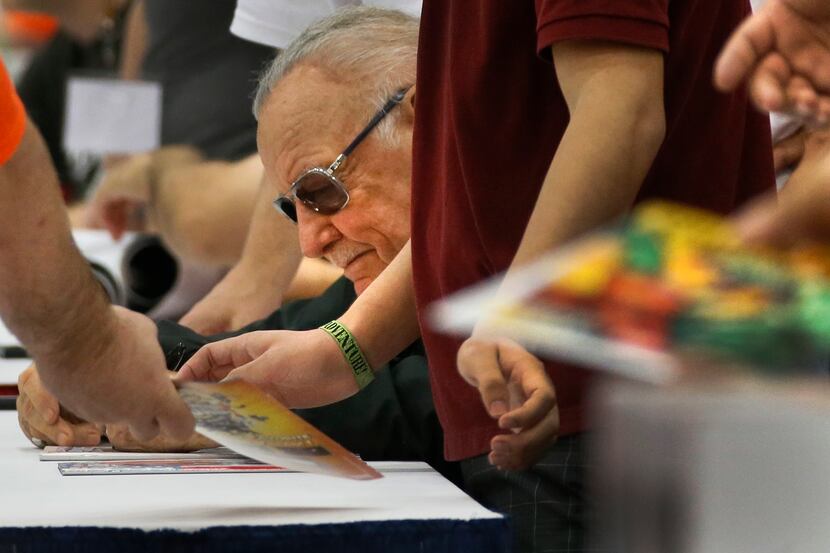 Comic book legend Stan Lee is surrounded by helpers and autograph seekers at Dallas Comic...