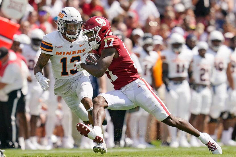 Oklahoma wide receiver Marvin Mims (17) carries past UTEP defensive back Dennis Barnes (13)...