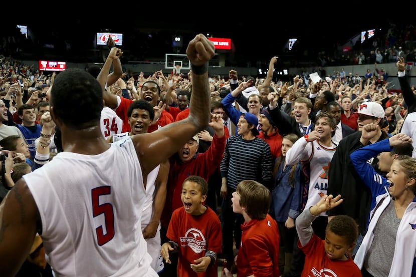 SMU's Markus Kennedy (5) (back to camera, left) cheers as fans storm the court following a...