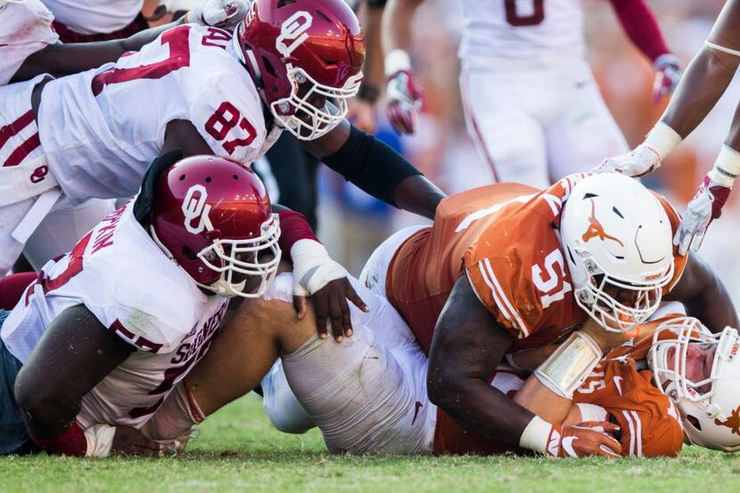 Texas Longhorns quarterback Sam Ehlinger (11) is pulled down by Oklahoma Sooners defensive...