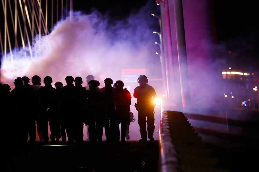 Police deploy crowd control chemical agents as they surround protesters who marched onto the...